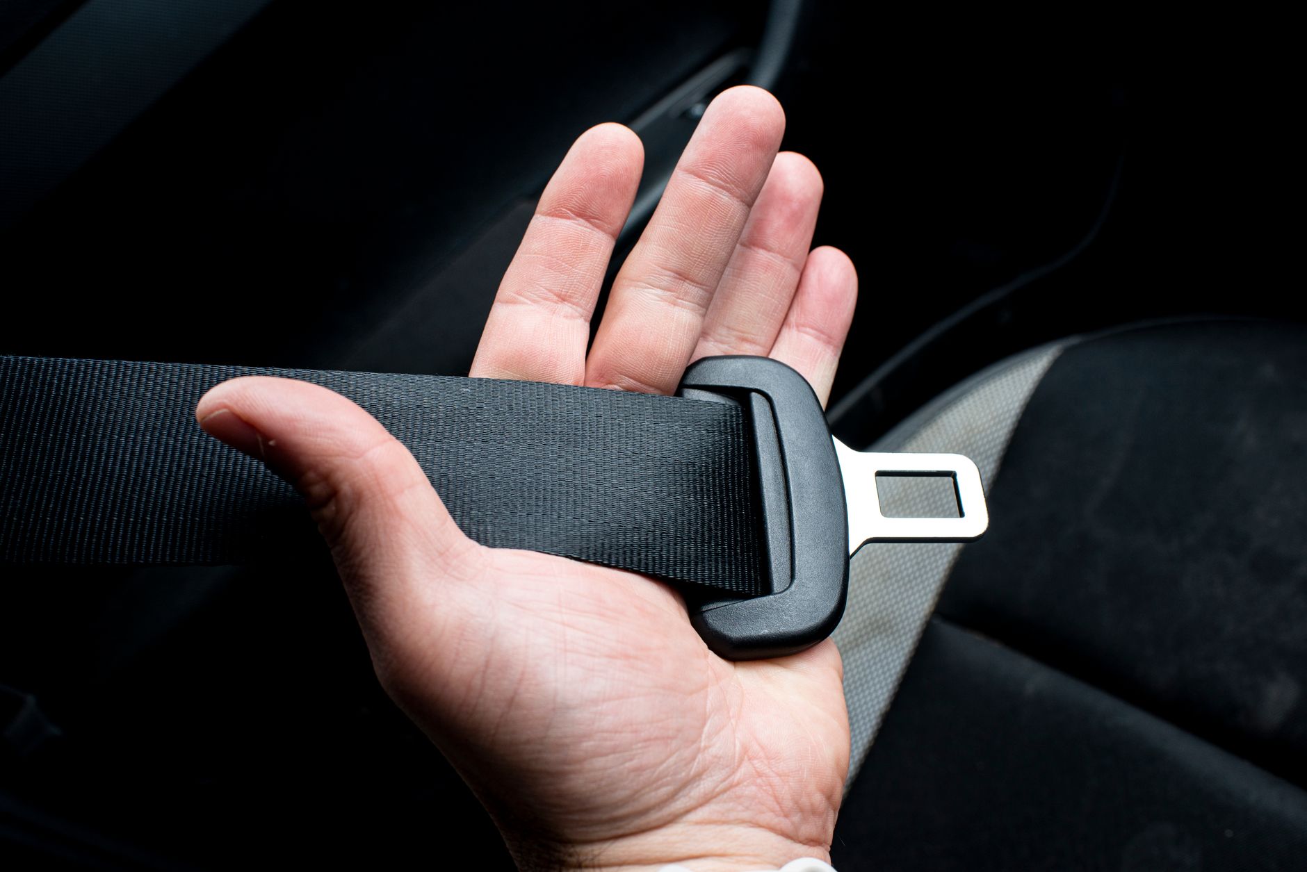 Mão a apertar o cinto de segurança dentro do carro